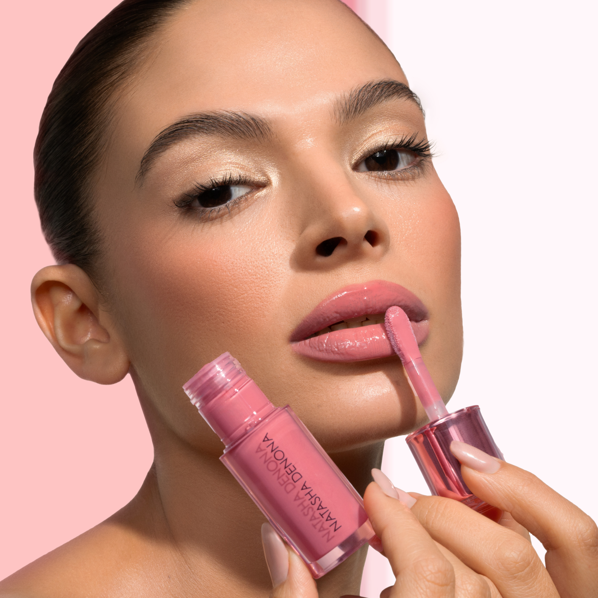 HY-GLOSS in shade 'Lush Lila' model look on a light-pink and white background. The model is applying the product on her lips.